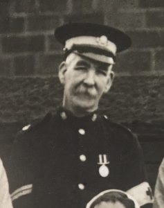 A man with a black uniform and white trimmings, wearing a medal.